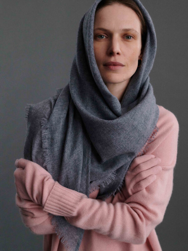 Modelka pozująca w szarej chuście na głowie i w pudrowych różowych rękawiczkach