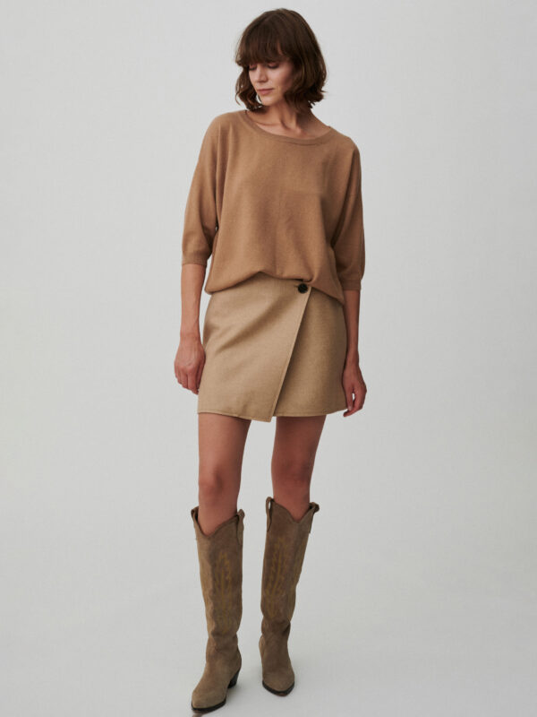 Modelka ubrana w sweter z krótkim rękawem w kolorze camel.