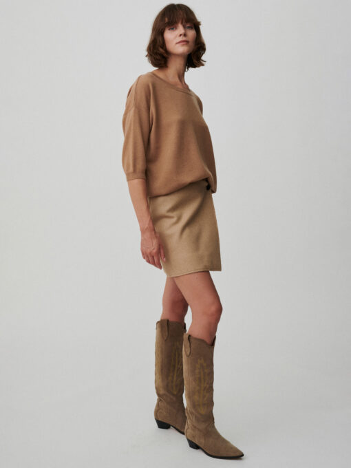 Modelka ubrana w sweter z krótkim rękawem w kolorze camel.