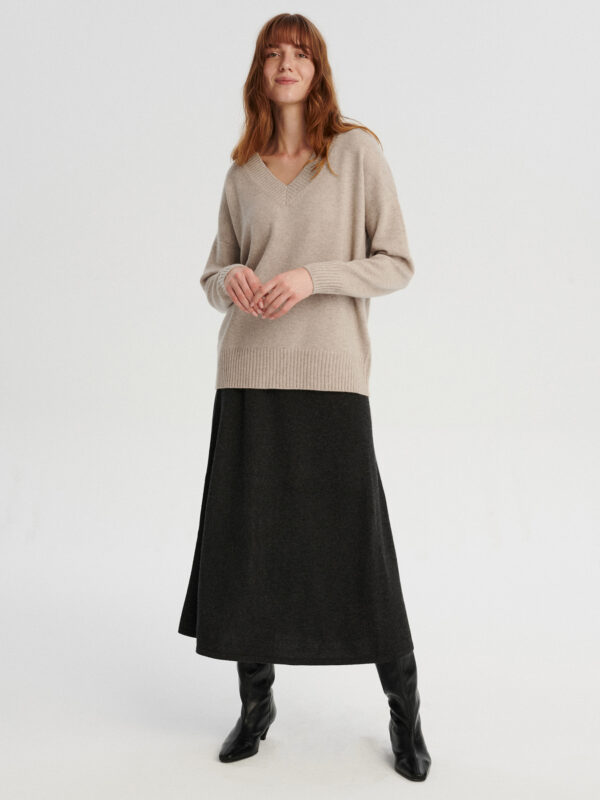 modelka w kaszmirowym swetrze w serek w kolorze chłodnego beżu