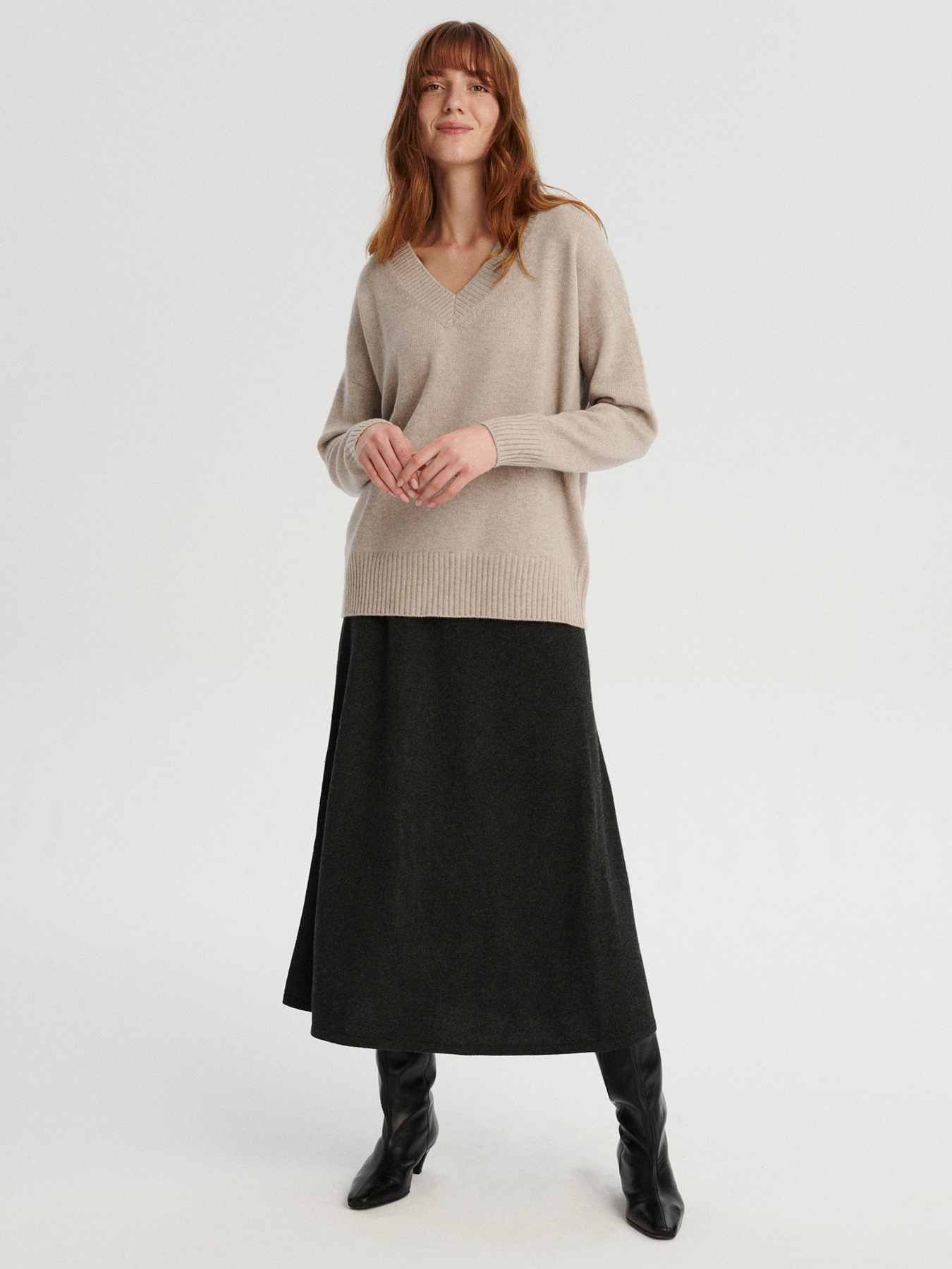 modelka w kaszmirowym swetrze w serek w kolorze chłodnego beżu