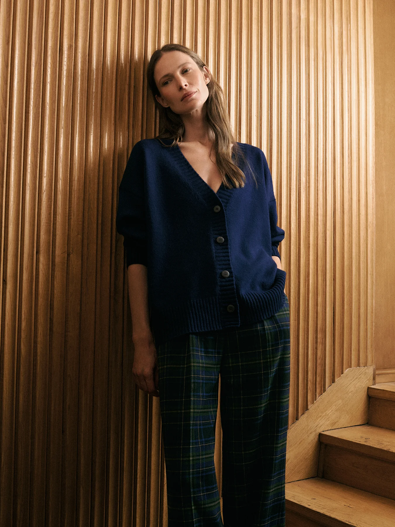 modelka w kaszmirowym granatowym kardiganie na tle ściany obitej drewnianą boazerią